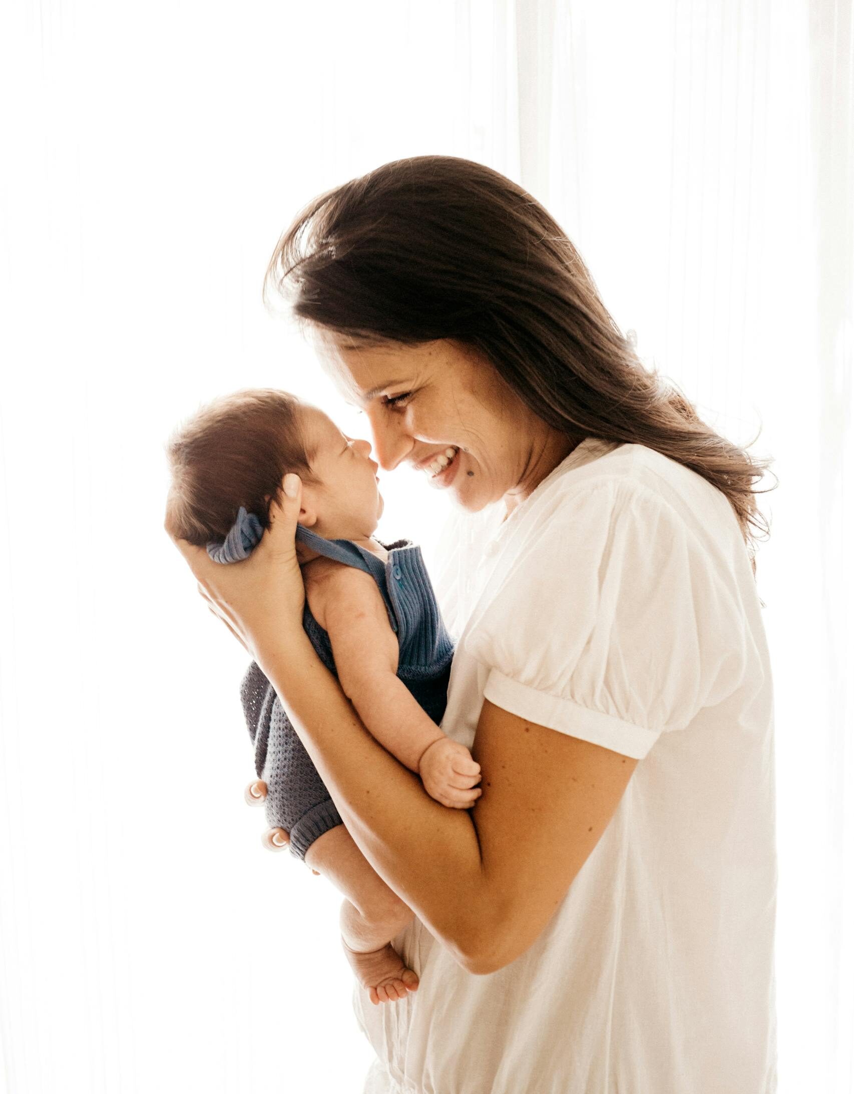 A joyful mother cradles her infant closely, expressing love and happiness.